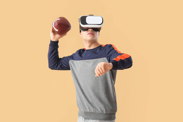 Joven deportivo con gafas de realidad virtual jugando fútbol americano sobre fondo de color - Foto, imagen