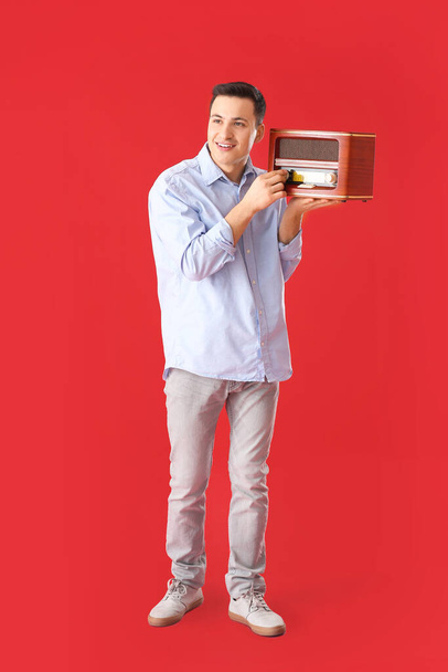 Mladý muž poslouchá retro rádio přijímač na barevném pozadí - Fotografie, Obrázek