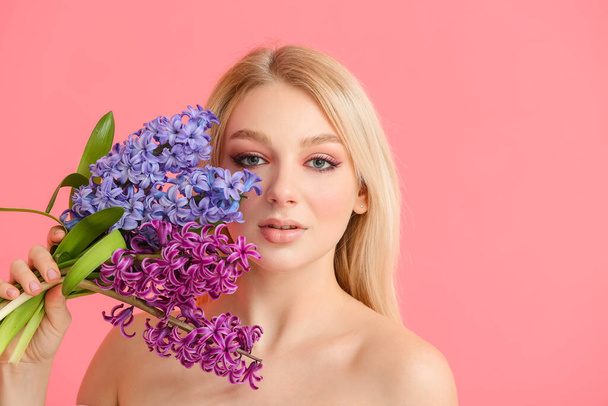 Beautiful young woman with hyacinth flowers on color background - Fotoğraf, Görsel