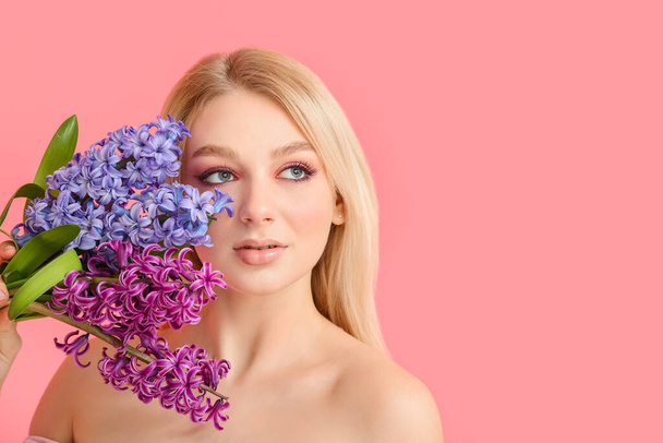 Beautiful young woman with hyacinth flowers on color background - Photo, Image