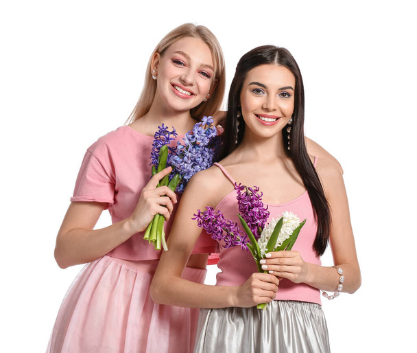 Belle giovani donne con fiori di giacinto su sfondo bianco - Foto, immagini