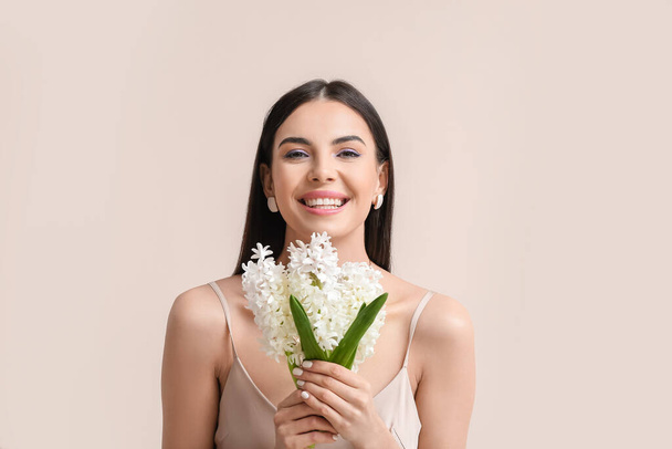 Beautiful young woman with hyacinth flowers on light background - Photo, image
