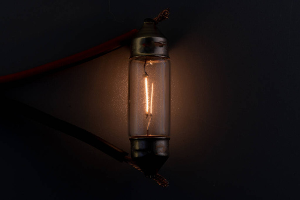 Car classic halogen bulb. Filament, glass and metal, high energy consumption. Black background. interior lighting. energized, working condition. Lights up - Photo, image