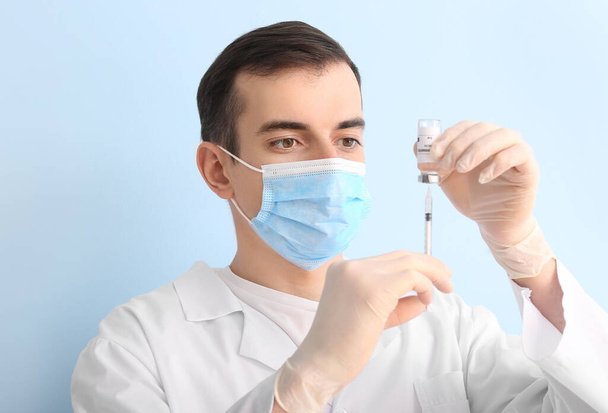 Doctor with vaccine on color background - Foto, afbeelding
