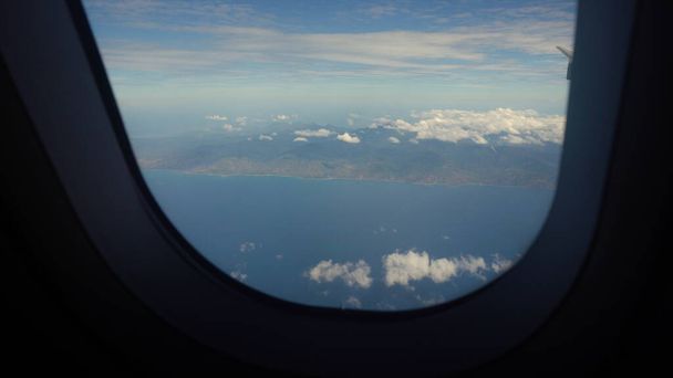 Θέα από ένα παράθυρο αεροπλάνου στον ωκεανό. - Φωτογραφία, εικόνα