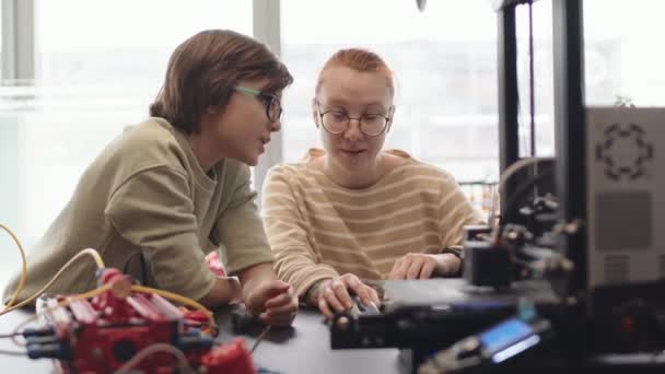 Aussperrung des kaukasischen Schülers und seiner jungen Lehrerin, die am Schreibtisch im Klassenzimmer sitzt und Laptop für die Analyse des Programmcodes benutzt, den der Junge für seinen Roboter gemacht hat - Filmmaterial, Video