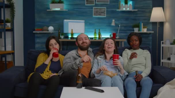 Amici multietnici ridendo mentre guardavano film comici godendosi il tempo trascorso insieme - Filmati, video