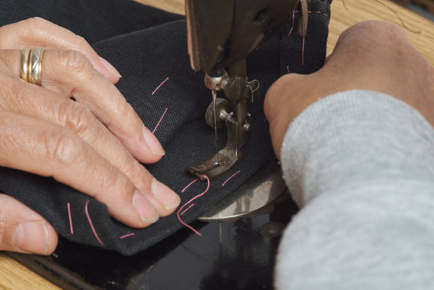 Close-up view of sewing process. Female hands stitching with a vintage sewing machine. Selective focus. - Photo, Image