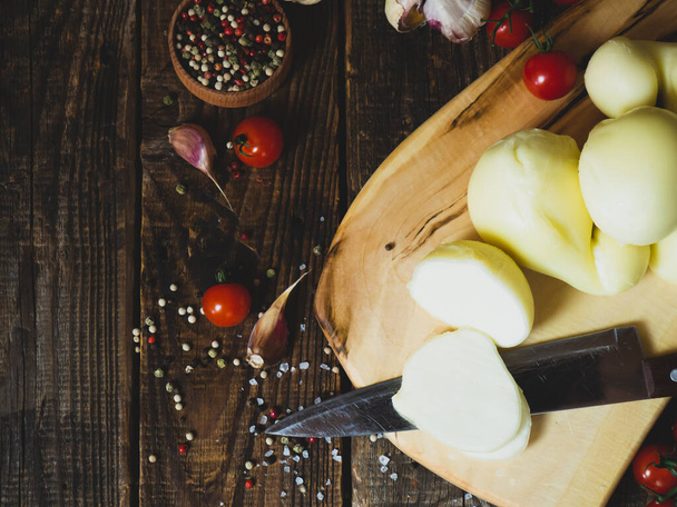 scamorza cheese.İtalyan caciocavallo peyniri ve kırmızı domatesler eski ahşap bir masa üzerinde, rustik arka plan - Fotoğraf, Görsel