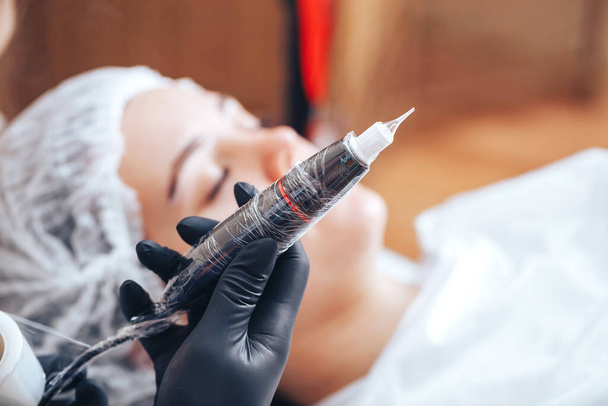 Frau bereiten Instrumente für permanente Make-up zu arbeiten Verwendung Folienband für Sterilität, Werkzeuge für Tätowierung gebrauchsfertig. - Foto, Bild
