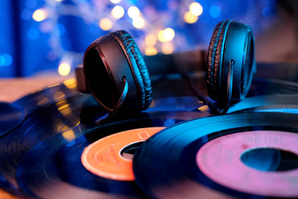 close-up black headphones on vinyl records, color backlighting, analogue retro music concept, audio experience, relaxation, musical enjoyment, vintage technologies - Foto, Imagem