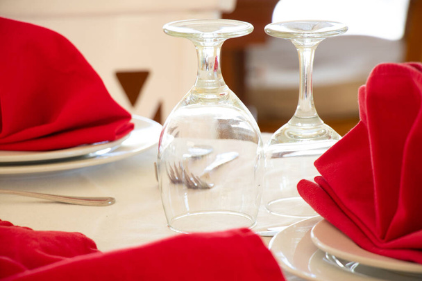 Послуги громадського харчування. Окуляри без вина і тарілок з червоною серветкою на білій скатертині, стіл для вечірки або весільного прийому, стіл для святкування
 - Фото, зображення