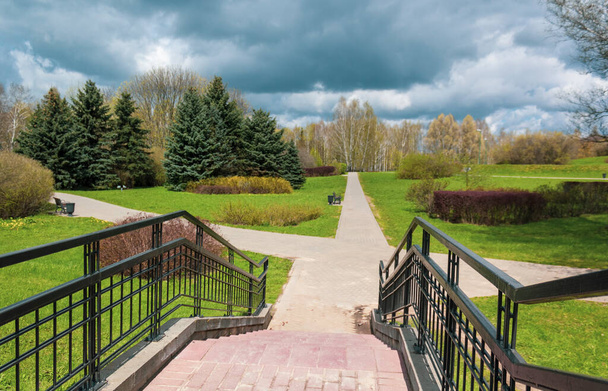 Metal staircase, descent to the park. Troubled sky in spring before rain. - Photo, Image