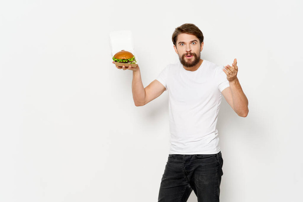 mies valkoisessa t-paidassa hampurilainen pikaruoka toimitus ruoka ruokavalio - Valokuva, kuva