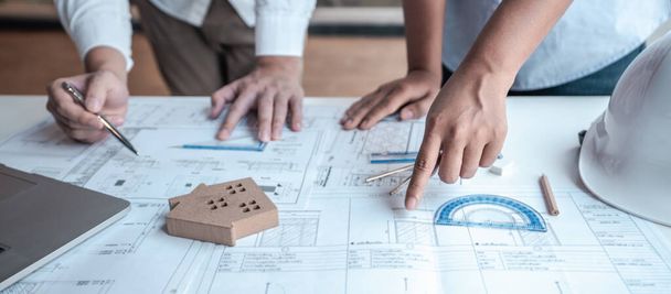 Team of architects or engineering consulting and analyzing working on objects tools and construction drawings inspection, discussing planning new architectural project on blueprint and model house. - Photo, Image