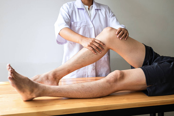Médico ou Fisioterapeuta trabalhando examinando o tratamento da perna lesionada do atleta paciente masculino, fazendo a terapia de reabilitação dor na clínica. - Foto, Imagem
