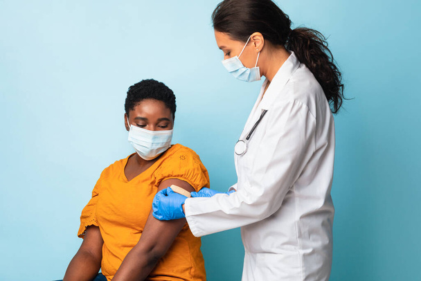 Arzt klebt Verband nach Impfung am Arm des Patienten, Studio - Foto, Bild