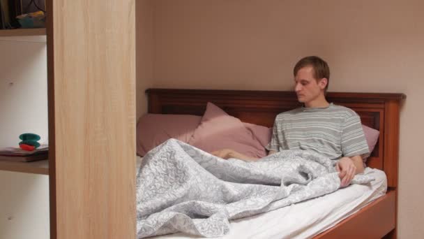 Mann mit Fernbedienung steigt aus dem Bett - Filmmaterial, Video