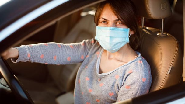 Nainen lääketieteellisessä naamiossa autossa. koronavirus, tauti, infektio, karanteeni, covid-19 - Valokuva, kuva