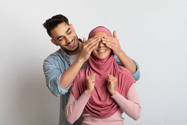 Στοργικός ισλαμιστής σύζυγος που εκπλήσσει τη μουσουλμάνα γυναίκα του με χιτζάμπ. - Φωτογραφία, εικόνα