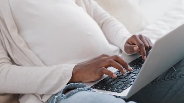 Close-up africana donna incinta mani femminili con pancia pancia digitando sulla tastiera utilizza il computer portatile per chattare. Irriconoscibile futura madre afro black lady che lavora a distanza ordina prodotti shopping online - Filmati, video