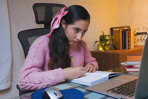 Millenniumi tinédzser kaukázusi diák, aki házi feladatot csinál otthon. Fiatal lány jegyzetel a laptopja előtt, videohívás otthonról, iskola otthon - Fotó, kép