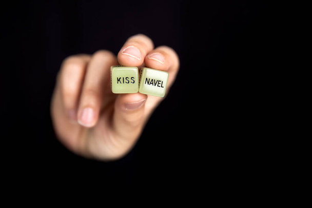 Ruka drží dvě kostky s erotickým textem pro sexuální hru na tmavém černém pozadí s kopírovacím prostorem, sex, láska, dospělý, koncept hry - Fotografie, Obrázek