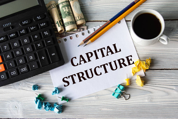 CAPITAL STRUCTURE - words on a white sheet against the background of a calculator, banknotes, cups of coffee and pencils. Business concept - Foto, imagen