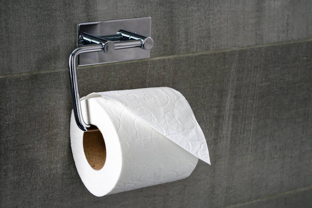 gros plan d'un rouleau de papier toilette sur un support en acier contre un mur de tuiles grises - Photo, image
