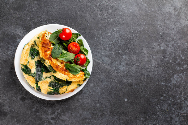 Frittata z vajec, sýra a špenátového salátu. Frittata - italská omeleta na bílém talíři na šedém pozadí. Ketogenní, keto jídlo, menu recept místo pro text, horní pohled - Fotografie, Obrázek