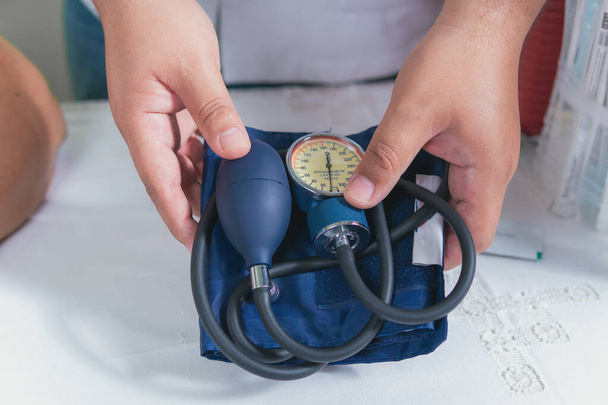 médico sostiene en sus manos un instrumento para medir la presión arterial - Foto, Imagen