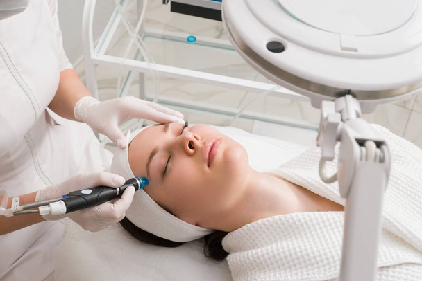 Een vrouw krijgt laserbehandeling van het gezicht in een kosmetologische kliniek, een concept van huidverjonging wordt ontwikkeld. laser peeling - Foto, afbeelding