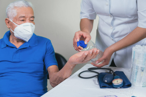 Uomo anziano che applica gel antibatterico sulle mani - Foto, immagini