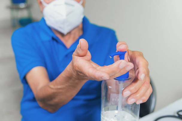 Senior man applying antibacterial gel on hands - Zdjęcie, obraz