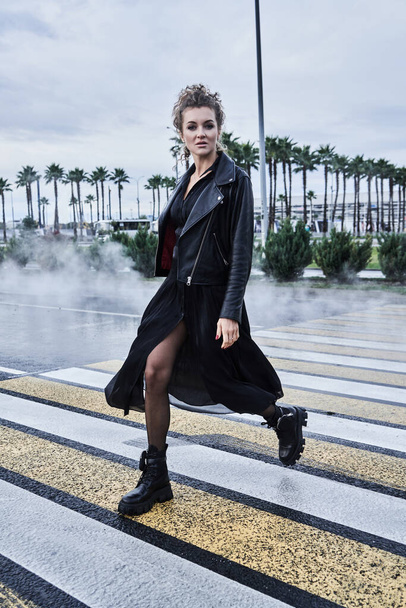 portrait of fashion model girl in black clothes crosses the city road - Foto, Bild