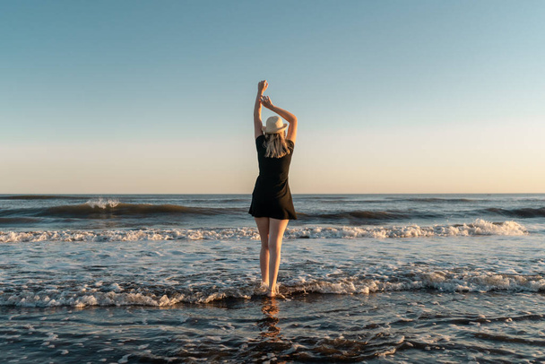 Blondi nainen rannalla auringonlaskun nauttien hänen vapautta ja vaikutusmahdollisuuksia. - Valokuva, kuva