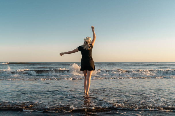 Ευτυχισμένη γυναίκα σε διακοπές χορεύει στην παραλία το ηλιοβασίλεμα - Φωτογραφία, εικόνα