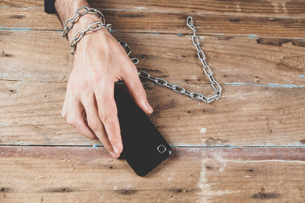 мужчина в наручниках, держащий телефон - Фото, изображение