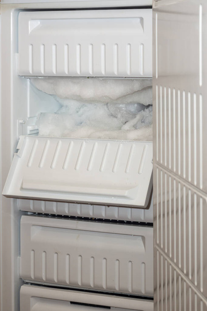 Il grande congelatore è aperto e una mensola è coperta di ghiaccio - Foto, immagini