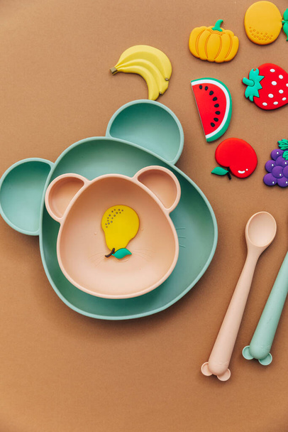 Bright silicone dishware on light background. Serving baby, first feeding concept. Flat lay, copy space, top view - Φωτογραφία, εικόνα