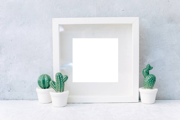 Minimal Mock up white frame with ceramic cactus plants in pots on a shelf or desk. White shelf and wall.  - Foto, Imagen