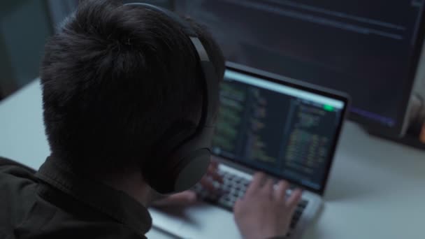Przystojny mężczyzna programista kody programowania podczas pracy za laptopem ze słuchawkami z domu. Inżynier IT w słuchawkach pracujących na komputerze w biurze. Wolni strzelcy, dystans społeczny - Materiał filmowy, wideo