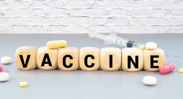 VACCINE word written on wood block with face mask and hand sanitizer. Text on wooden table for your desing, Wuhan coronavirus vaccine. - Photo, image