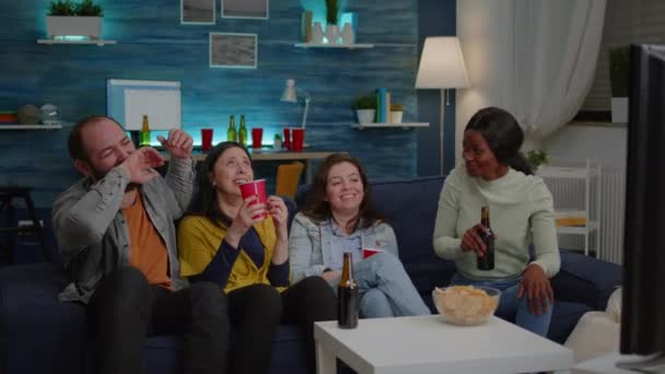 Felices amigos multiétnicos sonriendo juntos mientras están sentados en la helada de la televisión - Imágenes, Vídeo