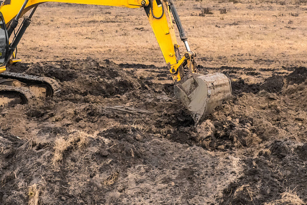 Sürüngen kazıcı ekipmanında inşaat işçisi sanayi bölgesinde bir çukur kazıyor. Toprak ve toprakla kazı çalışmaları. - Fotoğraf, Görsel