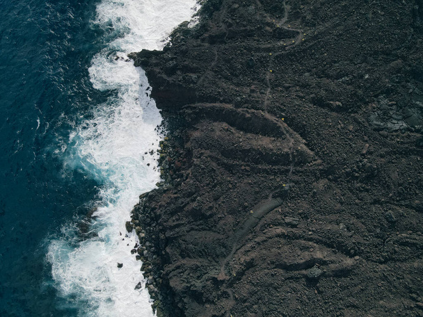 Aerial shot of waves crashing into a Hawaiian lava rock coast. drone. High quality photo - Photo, Image