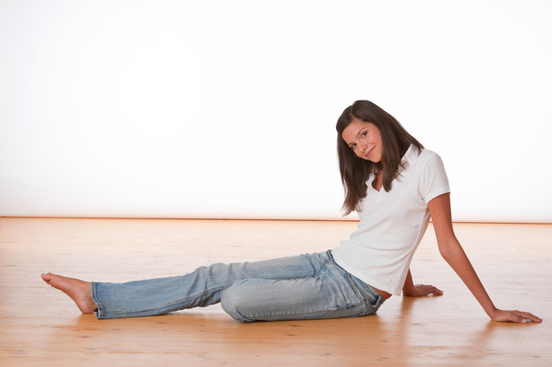 Happy teenager sitting on wooden floor - Zdjęcie, obraz