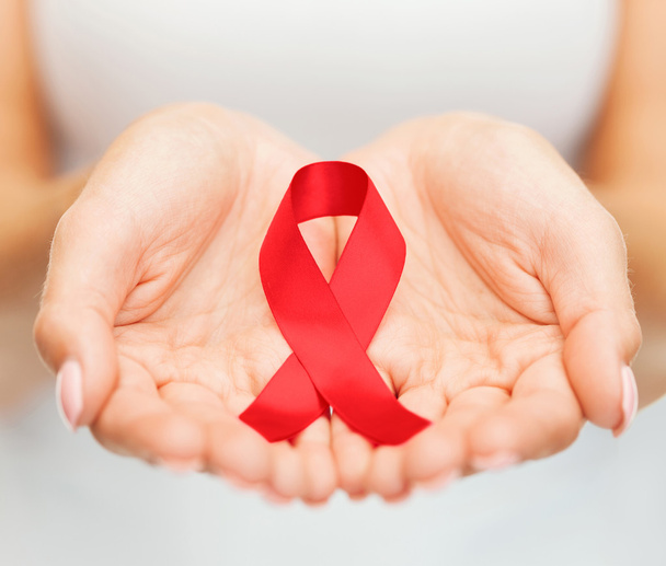 hands holding red AIDS awareness ribbon - Foto, Imagen