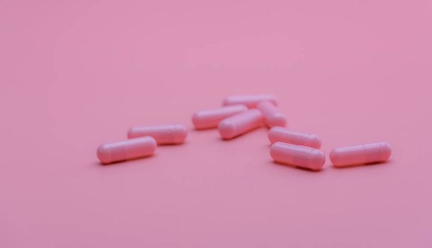 Pink capsules pill on pink background. Vitamins and supplements. Online pharmacy. Pharmacy store banner. Pharmaceutical industry. Woman's health insurance concept. Pills for love and happy life. - Foto, imagen