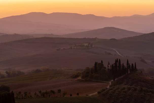 Pohled na krásné kopcovité toskánské pole ve zlatém ranním světle s cypřišovou farmou a balíky sena v Itálii. Val dOrcia - Fotografie, Obrázek